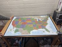 Full view of a colorful printed map of the United States spread flat on a table showing all states and borders.