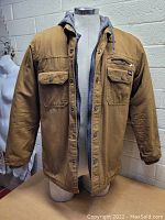 Front view of brown Dickies jacket with buttoned chest pockets and grey hooded lining on dress form.