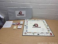 Photo showing the O.S.U.Opoly game board, game box, cards, dice, game tokens, play money, and instructions spread out on a table.