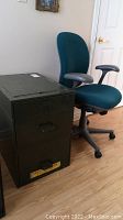 Side view showing metal two-drawer file cabinet next to adjustable office chair with teal fabric upholstery.