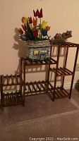 Wooden multi-level plant stand holding the tulip basket and ceramic bird figurines.