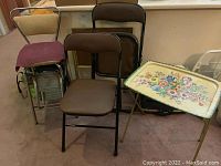 Shows all items together: two folding chairs, mid-century kitchen stool with cushioned seat cover, two folding TV trays including the floral tray