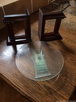 Pair of wooden book ends placed on a wooden surface with round glass display plate showing layered glass stepped design base