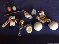 Various Christmas themed ornaments including snowman, bear, Santa face, white spherical ornaments, clear angel, green Santa with bell and ceramic Santa on sleigh.