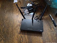 D-Link DIR-819 router on wooden surface with visible antennas and power adapter cable.