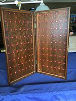 Front open view of wooden key cabinet showing two panels with evenly spaced red hooks for holding keys.