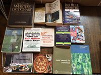 Photo showing a variety of 14 books including dictionaries, power prayers, real estate, microwaving, and rural Canada topics.
