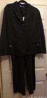Front view of black blazer jacket and trousers hanging on a door