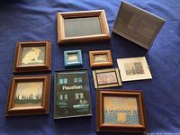 Nine assorted small picture frames of various sizes and styles displayed on a blue surface.