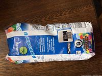 Sealed 2.3 kg bag of Mapei Keracolor unsanded grout, blue and white packaging with product info and color indication 'warm grey'.
