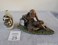 Both items displayed side by side: the ceramic Chinese hermit figurine on right and the Japanese ceramic porcelain sake bottle on left.