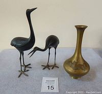 Overall view of bronze cranes and copper vase on fabric surface