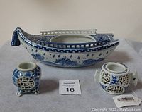 Three antique Japanese porcelain items: boat sashimi plate and two incense burners, arranged side by side on grey cloth.