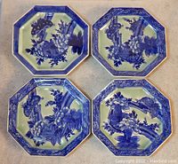 Four octagonal Japanese porcelain plates arranged in a group showing blue and white floral and butterfly design and decorative blue rim.