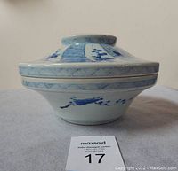 Side front view of Japanese porcelain bowl with lid, showing blue and white plum tree and fish scale decoration.