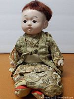 Full front view of doll seated wearing silk kimono