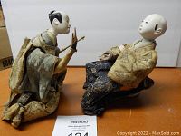 Two antique Meiji era Hina Ningyo dolls seated side by side, showing front profiles and traditional costumes with intricate fabric details.