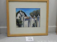 Framed oil pastel painting of a villa, showing full artwork with mat and light wood frame on floor.