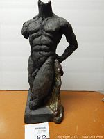 Front view of Sherri Cavan painted hard clay bust sculpture showing muscular torso, partial right arm draped with bronze-colored cloth, and absence of head and lower legs.