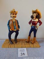 Front view showing both the cowboy and cowgirl sculptures standing on a wooden base