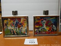 Two LeRoy Neiman ceramic whiskey decanters side by side, showing colorful sports-themed artwork of baseball and football scenes with silver caps.