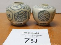 Two small blue and white porcelain jars side by side showing exterior decorated bodies and original inventory label on each jar