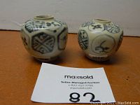 Front view of both blue and white patterned ceramic jars showing original provenance stickers