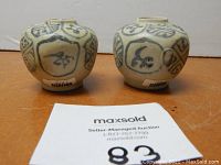 Front view photo showing the two jars side by side with inventory stickers on base