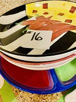 Stack of 3 colorful ceramic serving platters showing abstract and food-themed patterns.