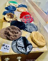 Overview of 15 assorted used hats in different styles and materials, arranged on a countertop.