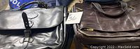 Black leather briefcase and brown leather laptop-style bag shown together