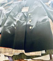 Close-up view of a double-breasted black suit jacket with gold buttons layered over other clothing items.