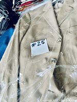 Beige suit blazer with button closure visible through protective plastic covering on hanger with label #25