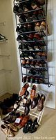 Tall shoe rack with multiple pairs of men's dress and casual shoes in shades of brown and black. Additional pairs displayed on the floor and a smaller rack, showing a variety of styles.