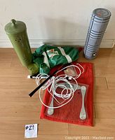 Multiple household items including scale, Gatorade bag, candle holder, candles, red rug, workout tube, and whip antenna arranged on floor.