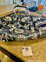 Photo of Roxy floral black and white roller bag showing handle and floral design.