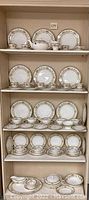 Four-shelf display showing plates and assorted cups and serving pieces