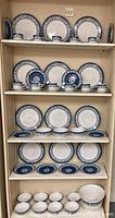 Full set displayed on shelves showing dinner plates, salad plates, mugs, saucers, and bowls.
