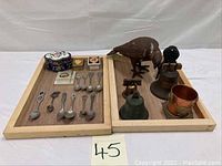 Overview of all small collectibles arranged in trays, including spoons, bells, iron bird, cloisonné box, and other items