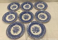 Eight Spode blue and white collector’s plates arranged on a surface, showing floral and decorative border patterns.