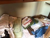 Photo of folded kitchen linens including chair covers, napkins, and tablecloths in multiple colors.