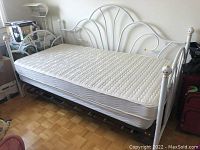 White metal frame day bed with mattress, showing full length of bed from side angle.