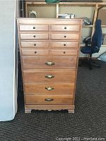 Front view of the six-drawer wooden highboy chest showing brass handles, round knobs, and medium wood finish.