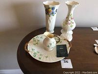 Overview of all Belleek China pieces on table: serving plate with clover design and two tall floral vases