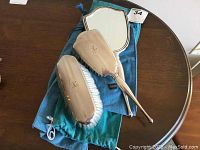 Three-piece dresser set on two Birks cloth bags: hand mirror, large hair brush, clothes brush