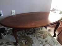 Full view of oval cherry coffee table showing top surface and leg style