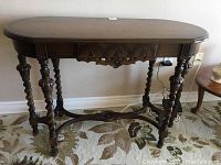 Front view of table showing oval top, carved apron, barley twist legs and stretcher