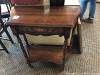 Front view of solid wood hallway table with worn surface and carved drawer front.