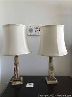 Front view of both marble base lamps with fabric shades, positioned side by side on a surface showing the overall appearance and condition.