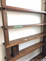 Full view of wooden bookshelf showing four horizontal shelves and pegged vertical supports.